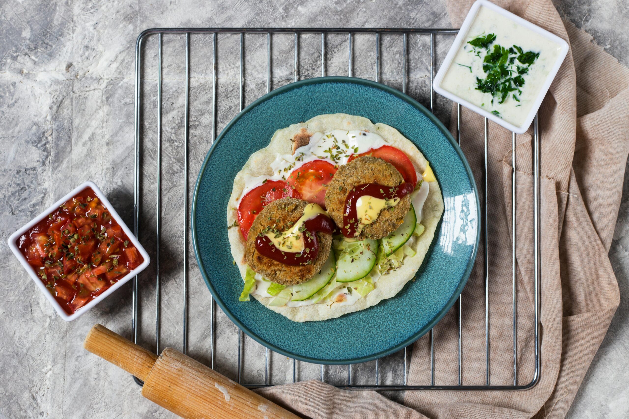 Top-down view of a vegan burger with fresh vegetables, salsa, and dips, perfect for gourmet cuisine lovers.